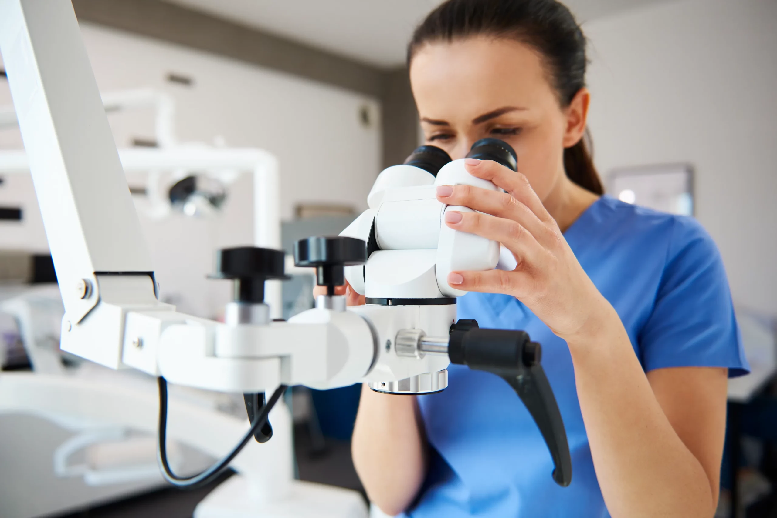 close-up-female-dentist-looking-through-dental-microscope